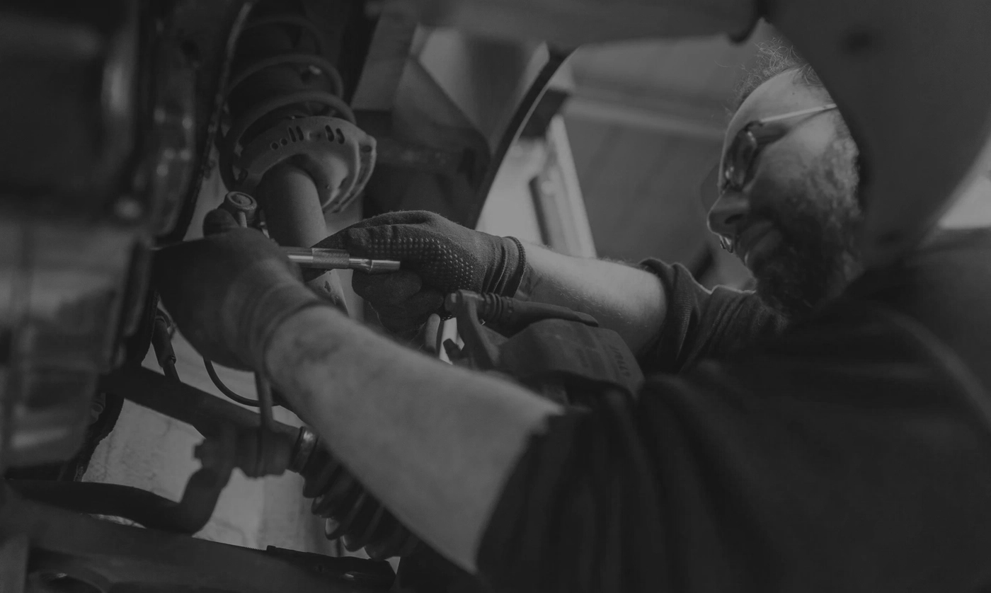 Nahaufnahme eines Mechanikers, welcher an einer Achse schraubt.